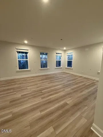 a view of an empty room with window and wooden floor