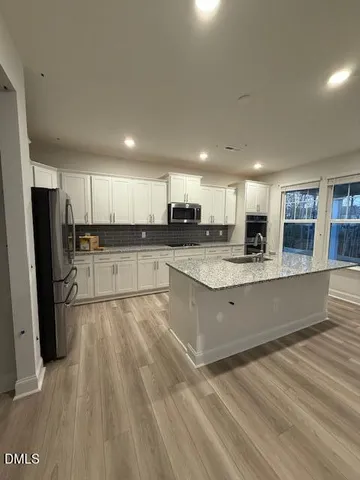 a large kitchen with granite countertop a large counter top stainless steel appliances and cabinets