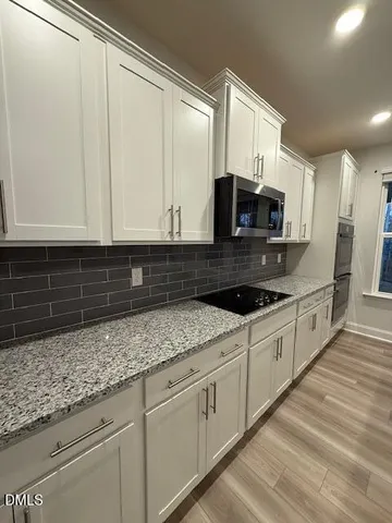 a kitchen with granite countertop white cabinets white stainless steel appliances and a sink
