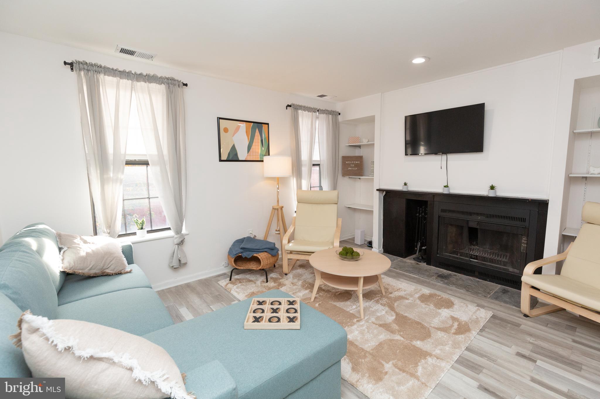 1915 Pemberton Street, Unit 2 Philadelphia, PA 19146 - Photo 2 of 16 a living room with furniture a flat screen tv and a fireplace