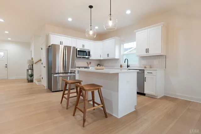 a kitchen with stainless steel appliances white cabinets a sink and a stove