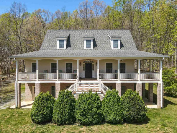 a view of a white house with large windows and a yard with plants and trees