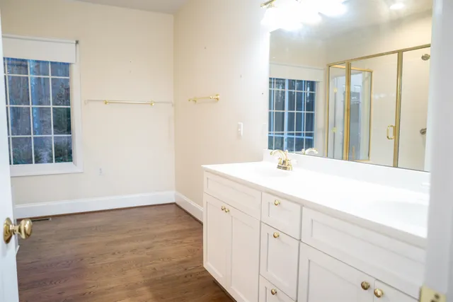 a spacious bathroom with a double vanity sink a large mirror and a shower
