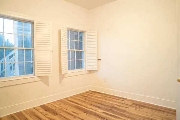 a view of an empty room with a window and wooden floor