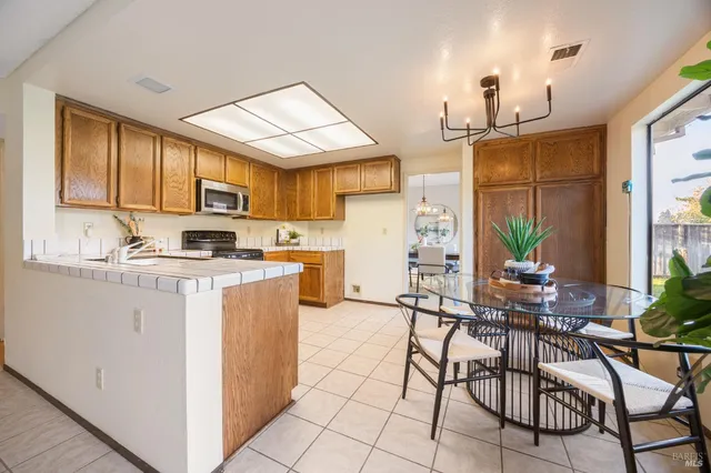 a kitchen with kitchen island granite countertop a stove a sink a dining table and chairs with wooden floor