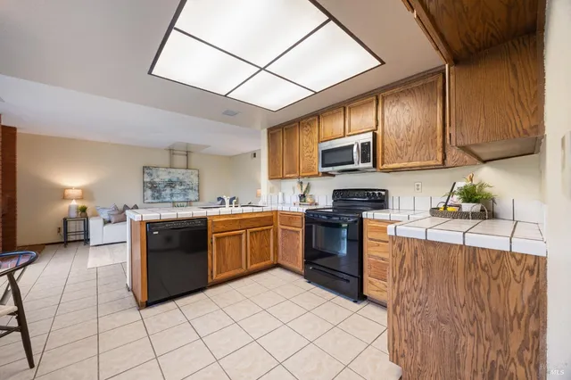 a kitchen with stainless steel appliances granite countertop a stove a sink dishwasher and a refrigerator with cabinets
