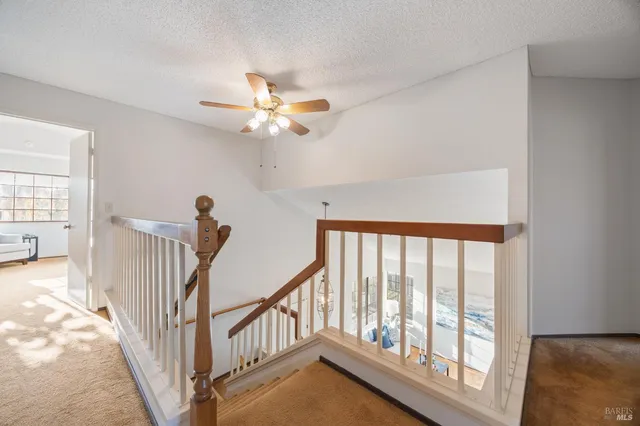 a view of a livingroom with wooden floor a ceiling fan and windows