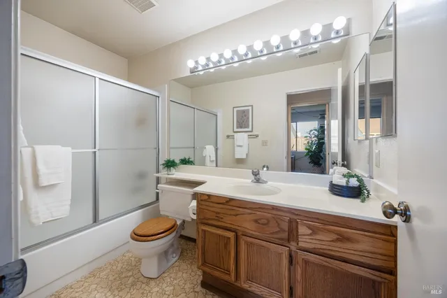 a bathroom with a granite countertop sink a toilet a mirror and shower