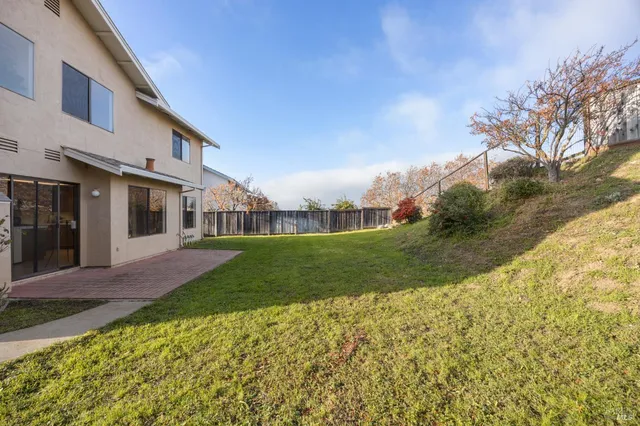 a view of a white house next to a yard with big trees