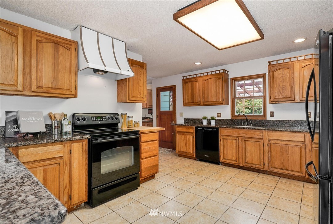 17002 Southeast 128th Street Renton, WA 98059 - Photo 9 of 30 a kitchen with stainless steel appliances granite countertop a stove sink and cabinets