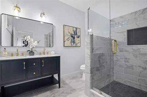 a bathroom with a sink a toilet a mirror and shower