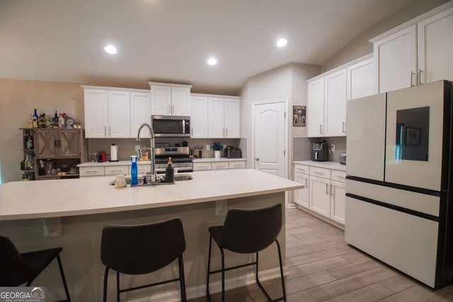 a kitchen with a sink a microwave a refrigerator and white cabinets