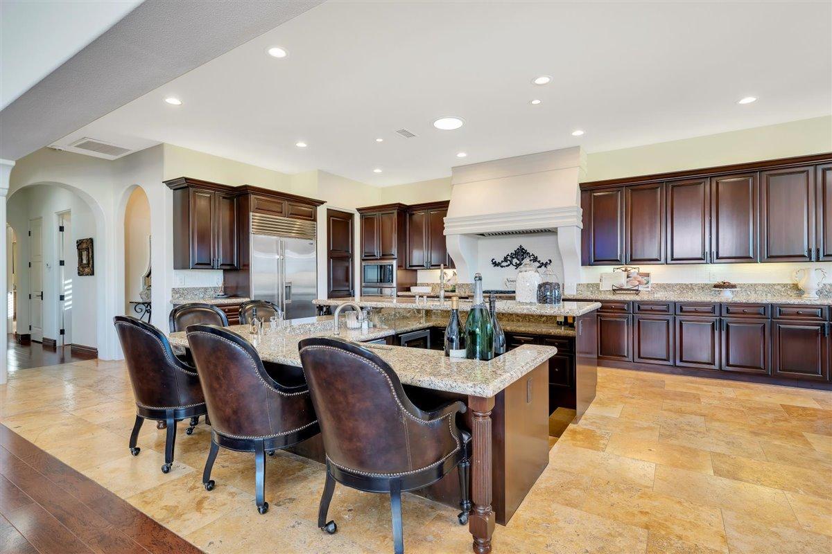 58445 Carmona La Quinta, CA 92253 - Photo 14 of 70 a kitchen with stainless steel appliances granite countertop a table chairs sink refrigerator and cabinets