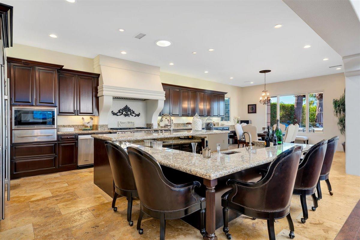 58445 Carmona La Quinta, CA 92253 - Photo 15 of 70 a kitchen with granite countertop a table chairs microwave and cabinets