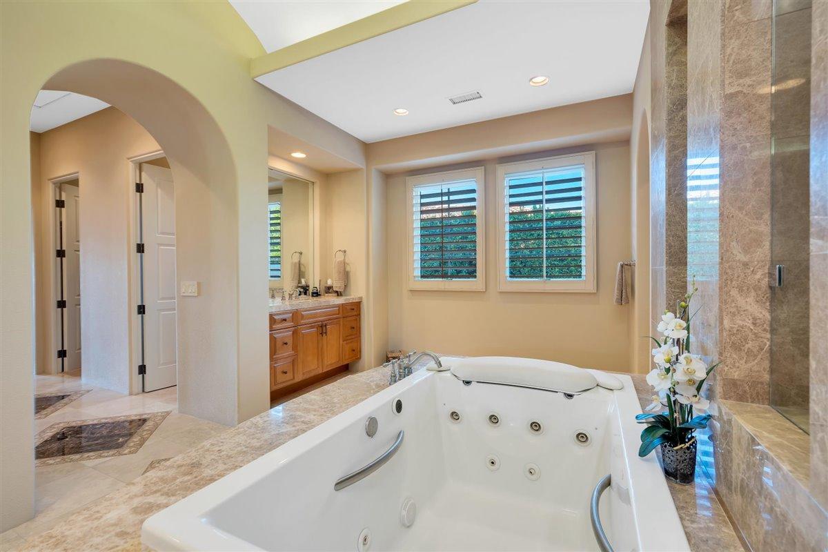 58445 Carmona La Quinta, CA 92253 - Photo 22 of 70 a spacious bathroom with a granite countertop tub a sink and a large mirror