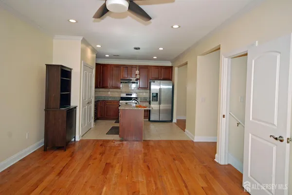 a kitchen with stainless steel appliances granite countertop a refrigerator and a wooden floor