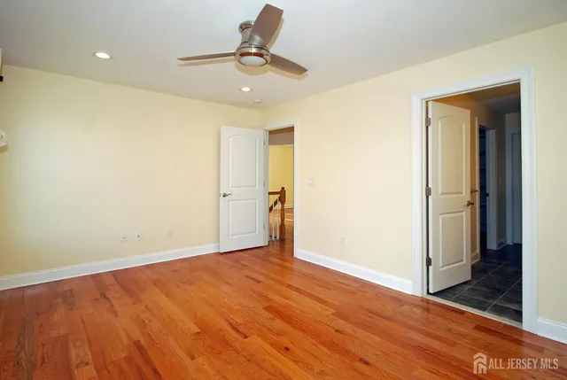 an empty room with wooden floor and a hallway