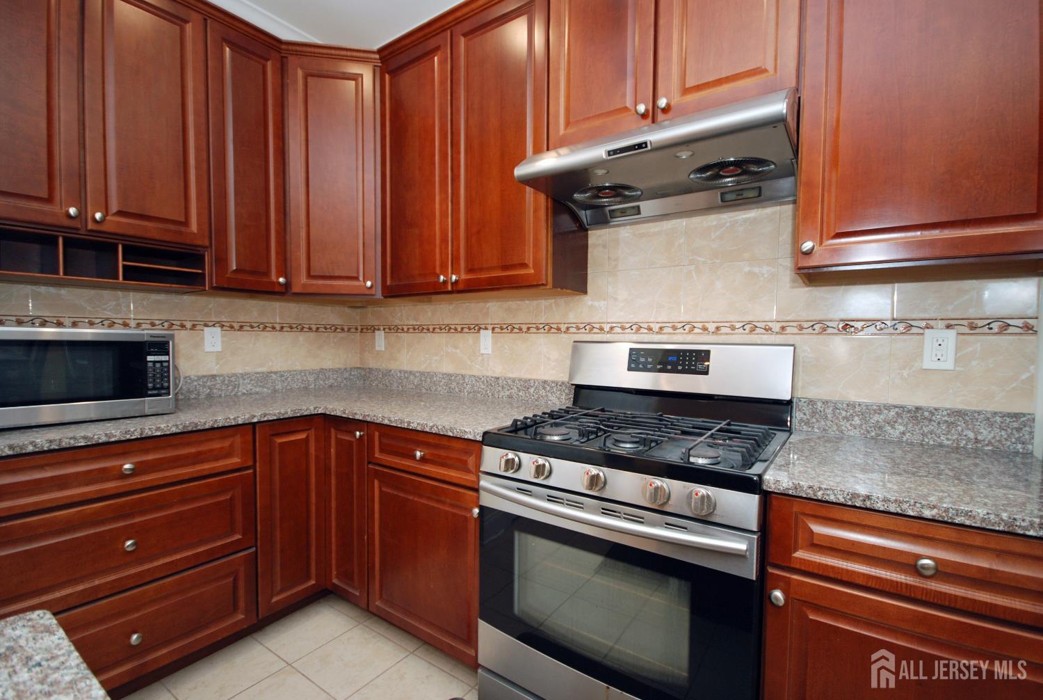 32 Cinder Road, Unit 3 Edison, NJ 08820 - Photo 9 of 34 a kitchen with granite countertop wooden cabinets and a stove top oven
