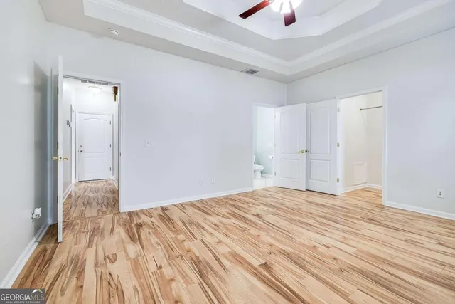 a view of a livingroom with a chandelier fan and wooden floor
