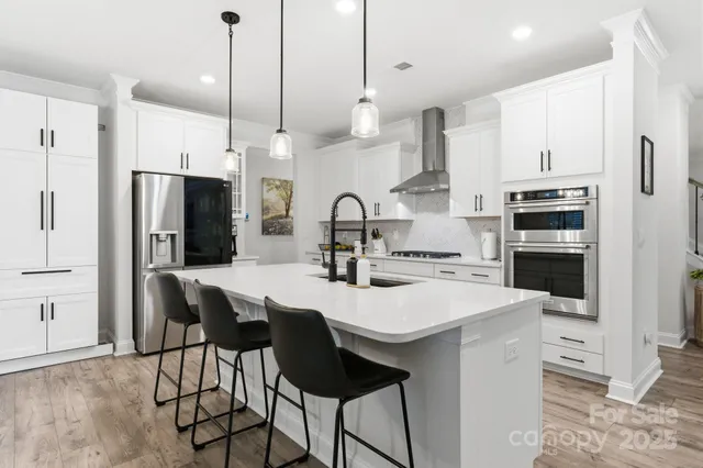 a kitchen with stainless steel appliances a stove a sink island and a refrigerator with wooden floor