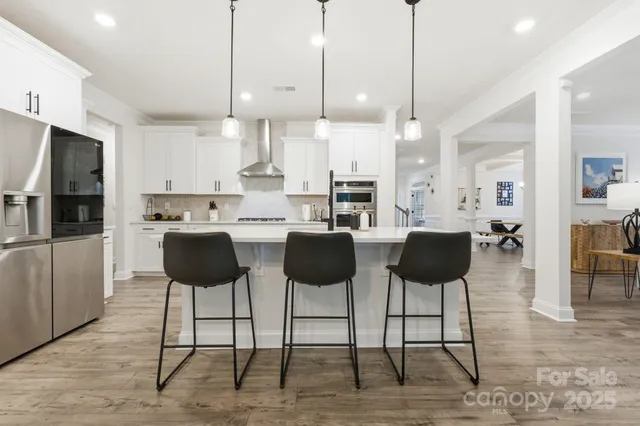 a kitchen with stainless steel appliances kitchen island granite counter tops chairs and a refrigerator