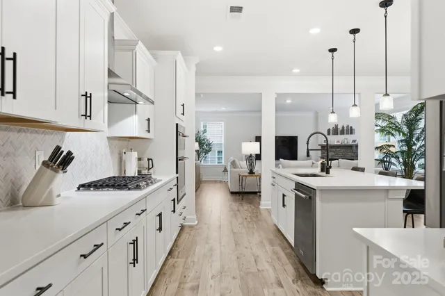 a kitchen with stainless steel appliances kitchen island granite countertop a sink a stove and a wooden floors