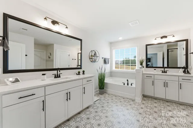 a spacious bathroom with double sink a large mirror and a bathtub