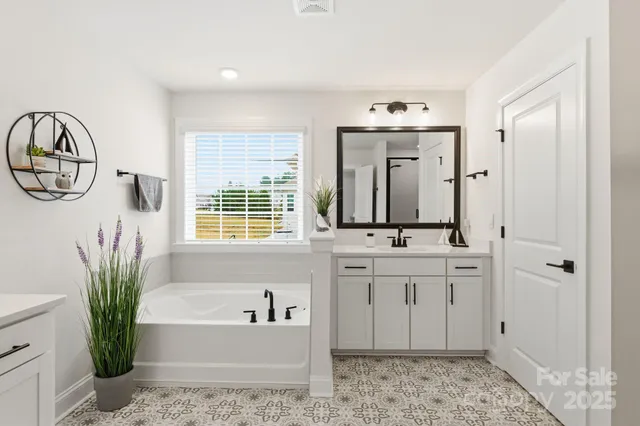 a bathroom with a tub a sink and a large mirror