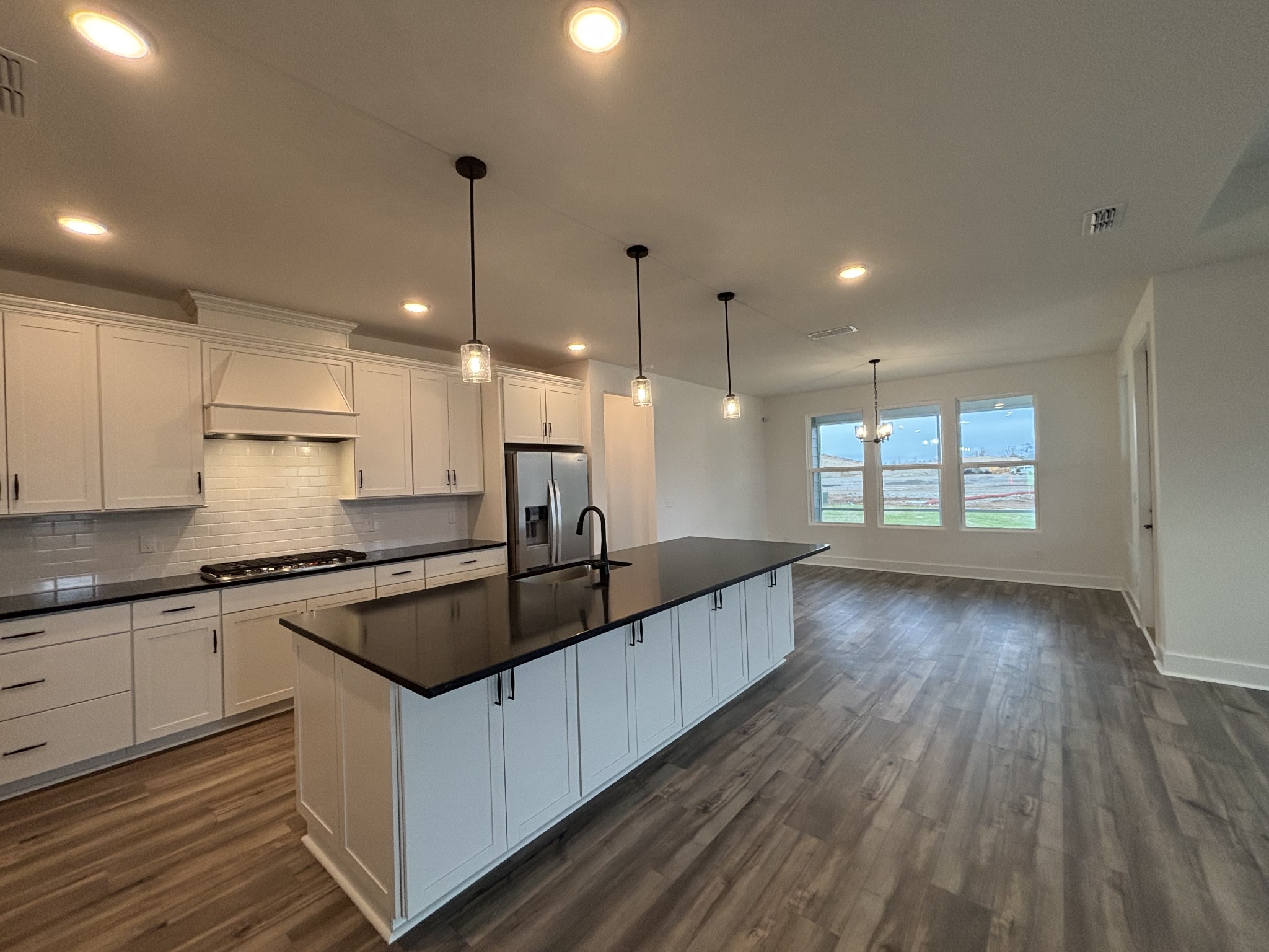 21 Pinnacles Lane Lebanon, TN 37090 - Photo 9 of 81 a kitchen with granite countertop a stove a sink wooden floor cabinets and a dining table with wooden floor