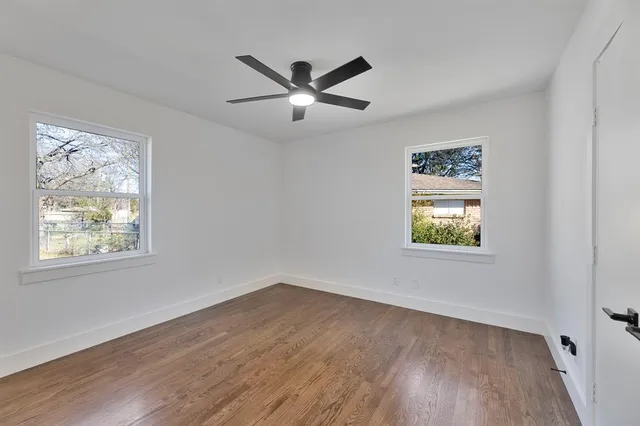 a view of empty room with wooden floor and fan