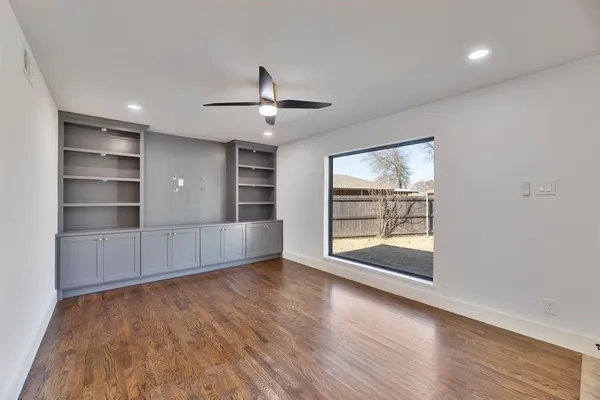 a view of an empty room with a window and wooden floor