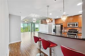 3300 Windy Ridge Parkway Southeast, Unit 913 Atlanta, GA 30339 - Photo 2 of 28 a kitchen with stainless steel appliances kitchen island granite countertop a refrigerator a stove and a wooden floors