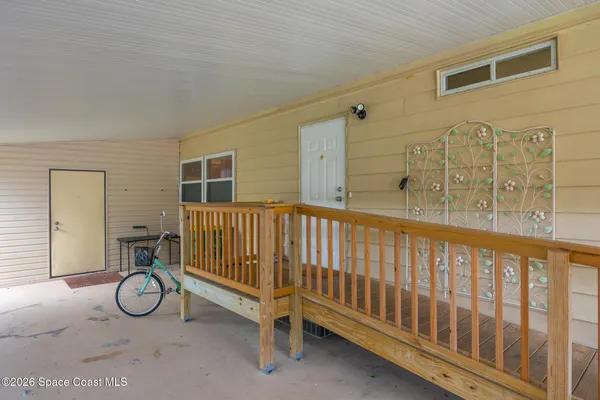 a view of porch with a small yard and potted plants