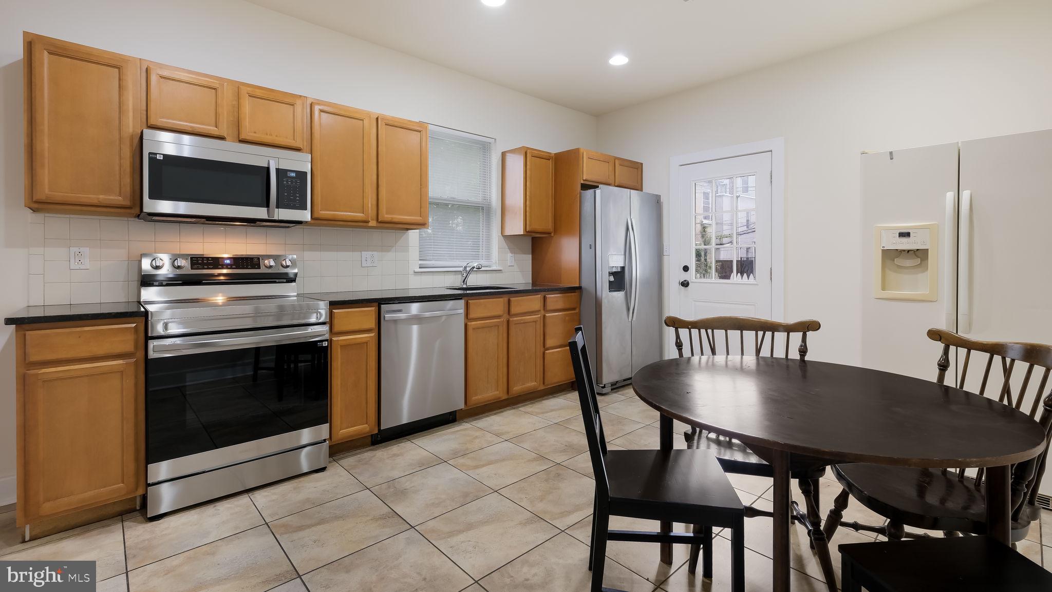 436 Sloan Street Philadelphia, PA 19104 - Photo 6 of 21 a kitchen with stainless steel appliances granite countertop a stove a microwave a dining table and chairs