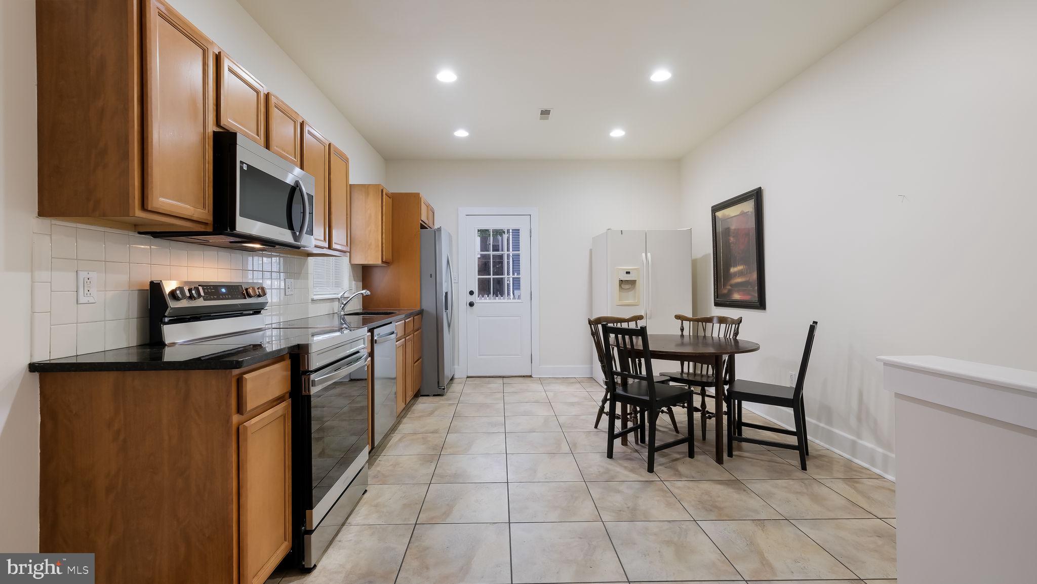 436 Sloan Street Philadelphia, PA 19104 - Photo 8 of 21 a kitchen with stainless steel appliances granite countertop a stove a sink a microwave a dining table and chairs