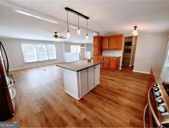 a kitchen with stainless steel appliances granite countertop a refrigerator a stove top oven a sink dishwasher and wooden floor