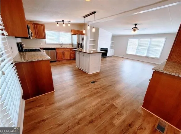 a view of kitchen and empty room with wooden floor