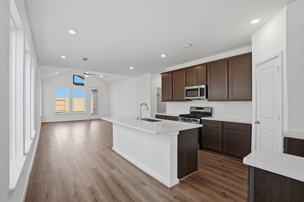 22122 Rangemore Drive Cypress, TX 77433 - Photo 3 of 28 a kitchen with stainless steel appliances granite countertop wooden cabinets a stove top oven a sink and dishwasher with wooden floor