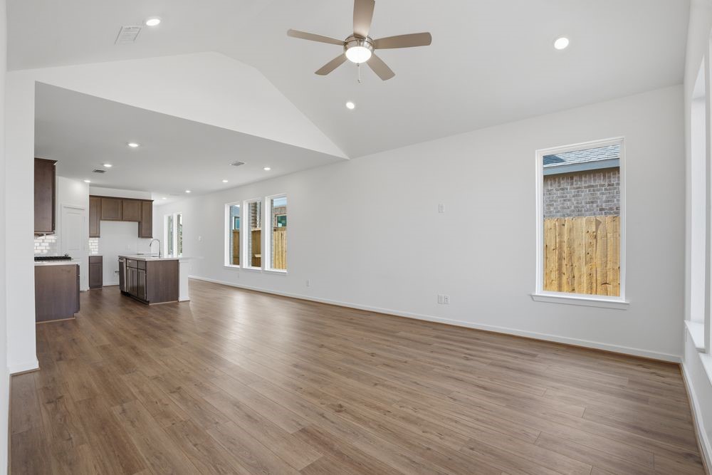 22122 Rangemore Drive Cypress, TX 77433 - Photo 5 of 28 an empty room with wooden floor a ceiling fan and kitchen view