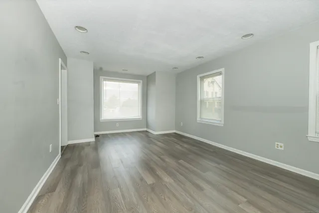 a view of an empty room with wooden floor and window