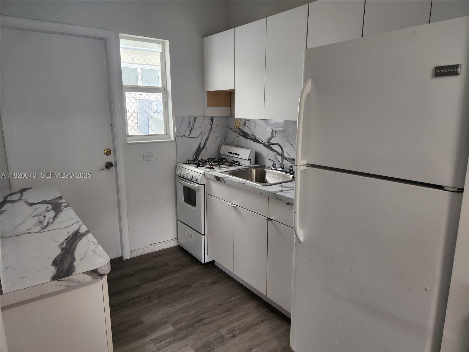 1239 Marseille Drive, Unit 4 Miami Beach, FL 33141 - Photo 13 of 15 a kitchen with a refrigerator sink and cabinets