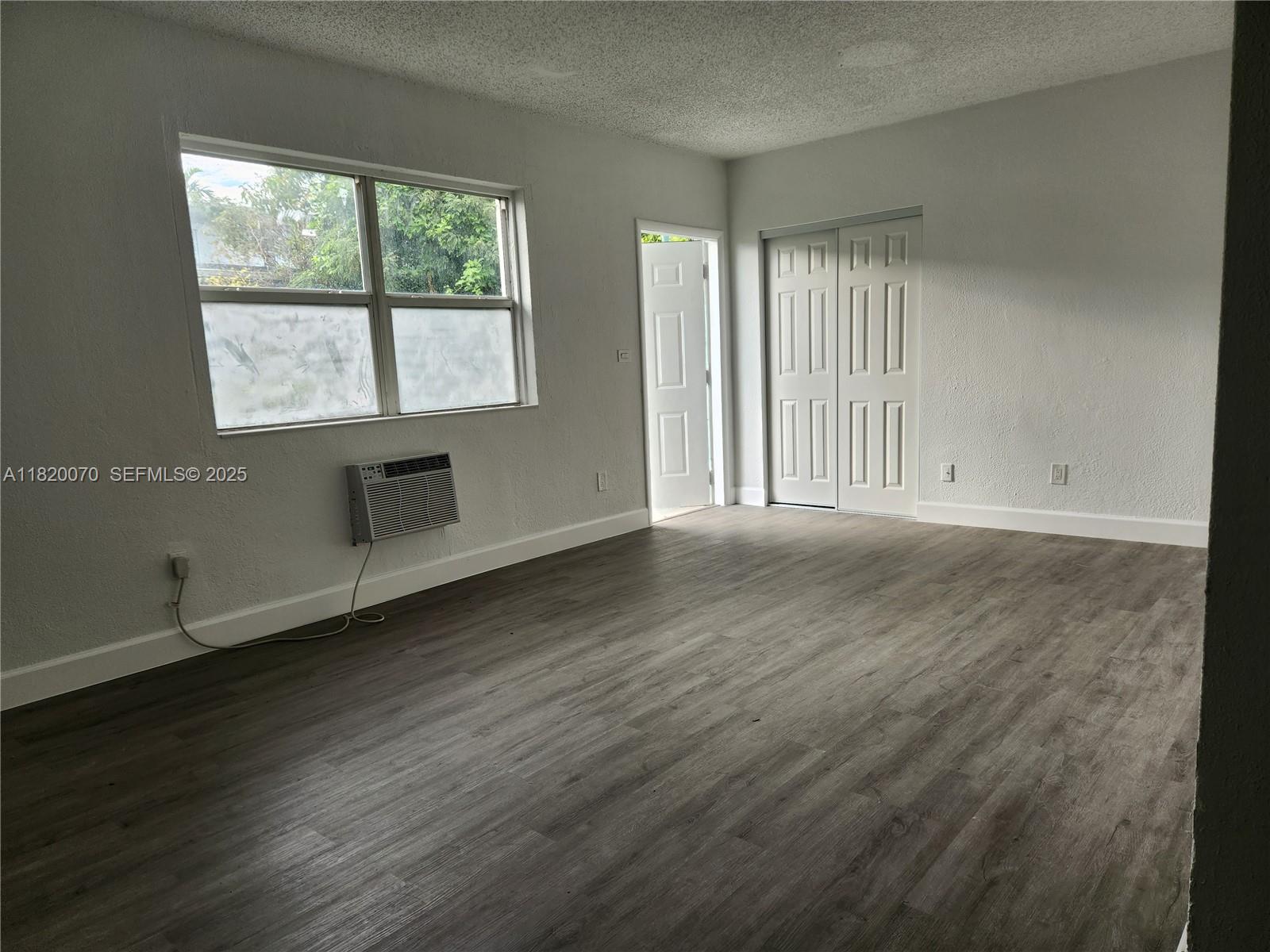 1239 Marseille Drive, Unit 4 Miami Beach, FL 33141 - Photo 14 of 15 a view of an empty room with wooden floor and a window