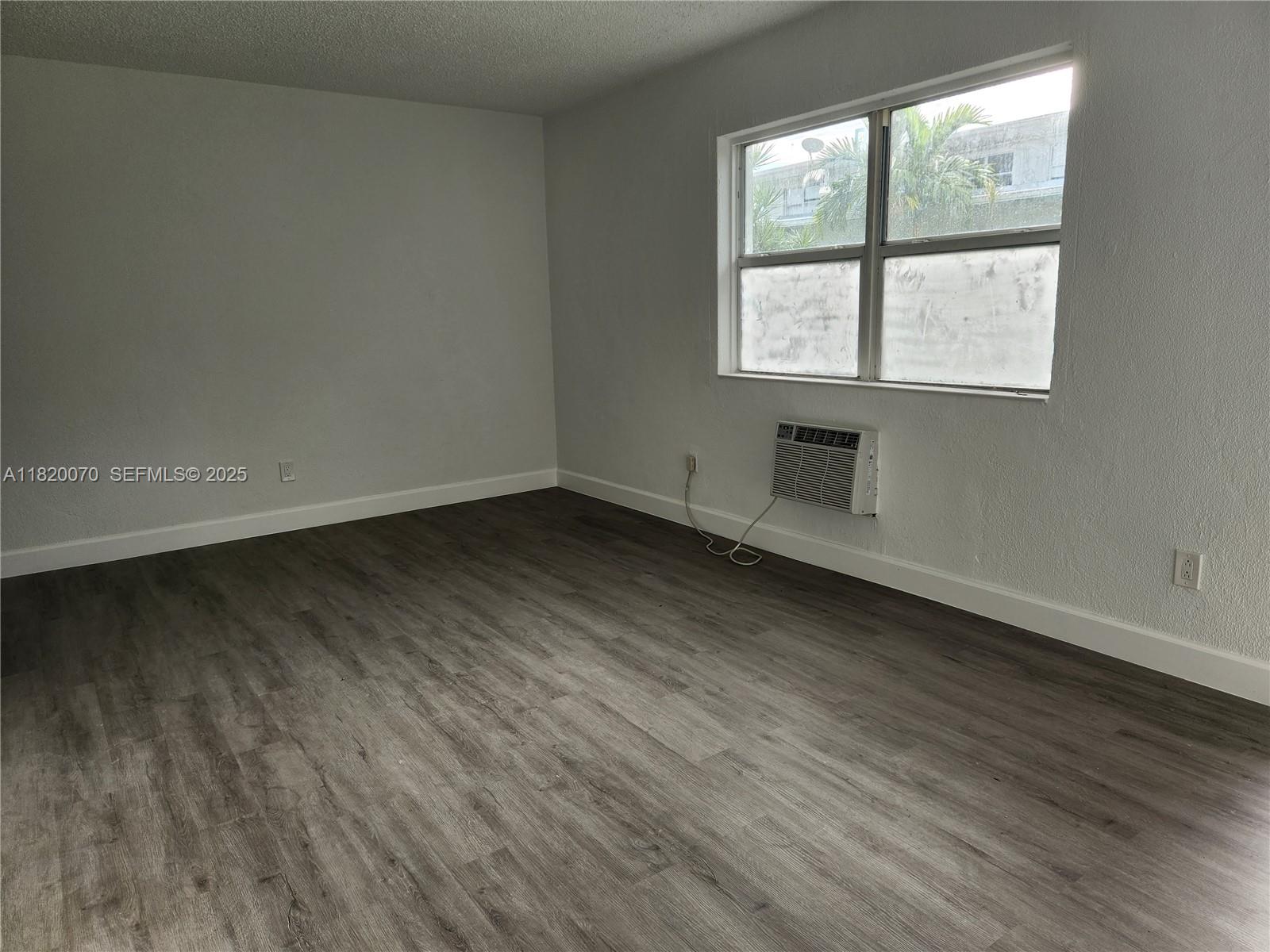 1239 Marseille Drive, Unit 4 Miami Beach, FL 33141 - Photo 7 of 15 an empty room with wooden floor and windows