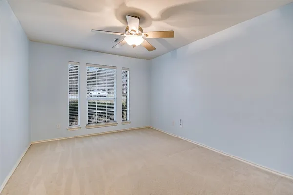 an empty room with chandelier fan and windows