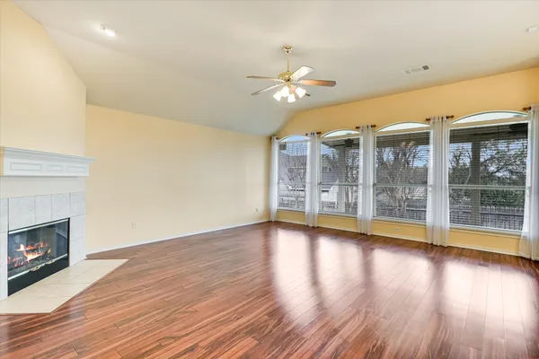 a view of an empty room with wooden floor and a fireplace