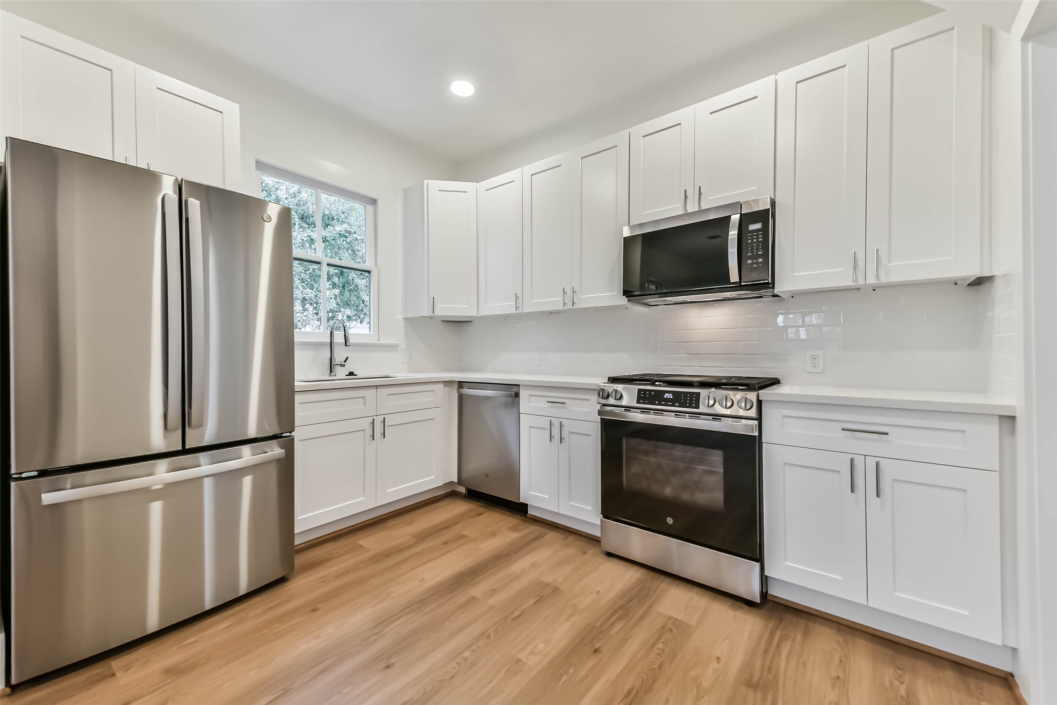 1616 38th Street Galveston, TX 77550 - Photo 12 of 26 a kitchen with cabinets stainless steel appliances and wooden floor
