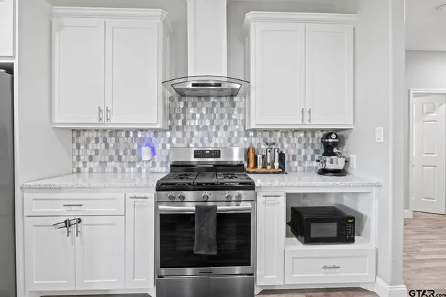 a kitchen with white cabinets and white stove