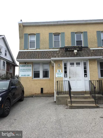 a view of a house with a barbeque and wooden bench