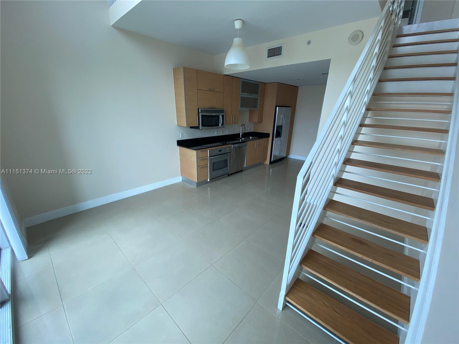 60 Southwest 13th Street, Unit 3003 Miami, FL 33130 - Photo 5 of 22 a view of an empty room with wooden floor and stairs