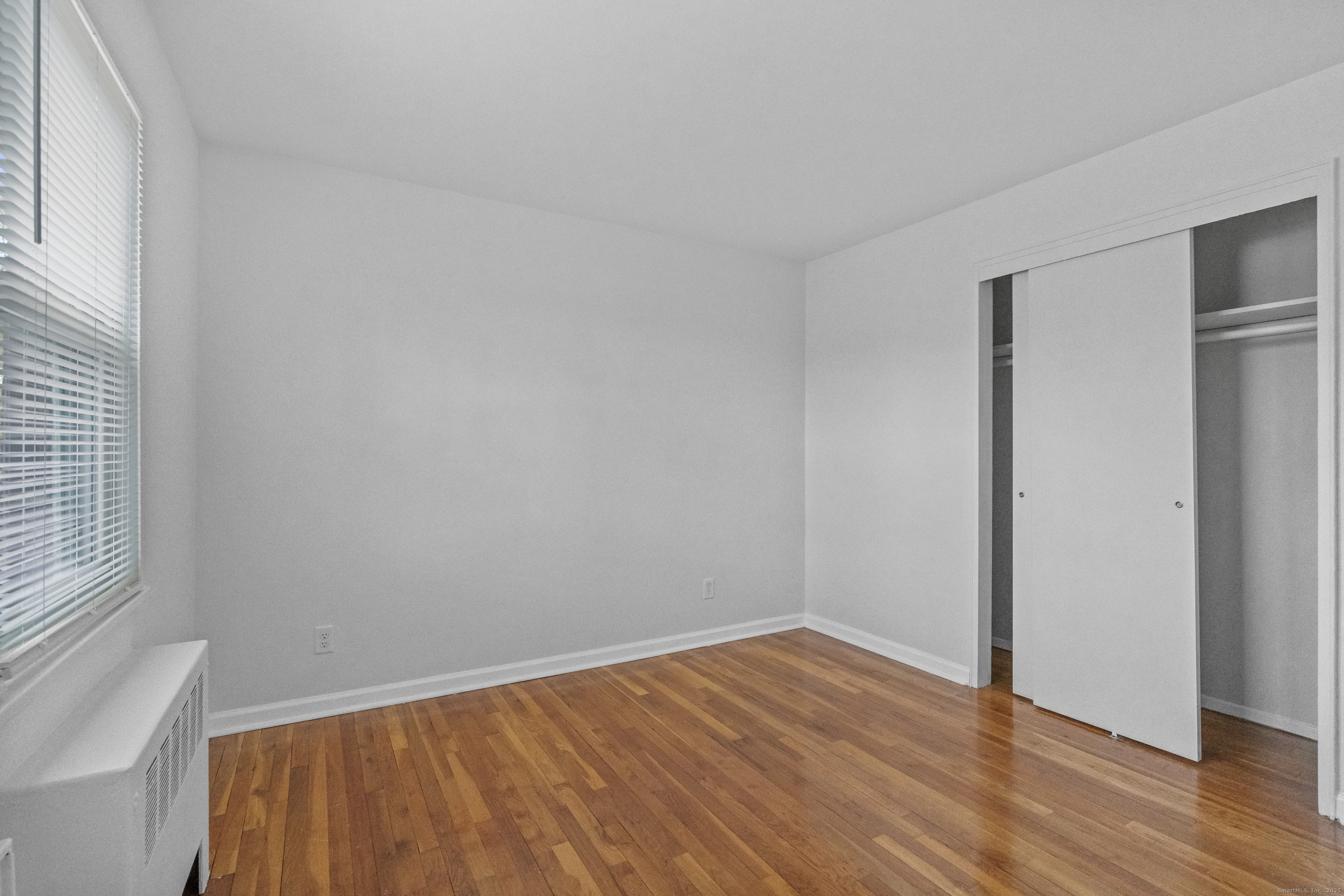 56 Blachley Road, Unit B Stamford, CT 06902 - Photo 11 of 26 a view of an empty room with wooden floor and a window